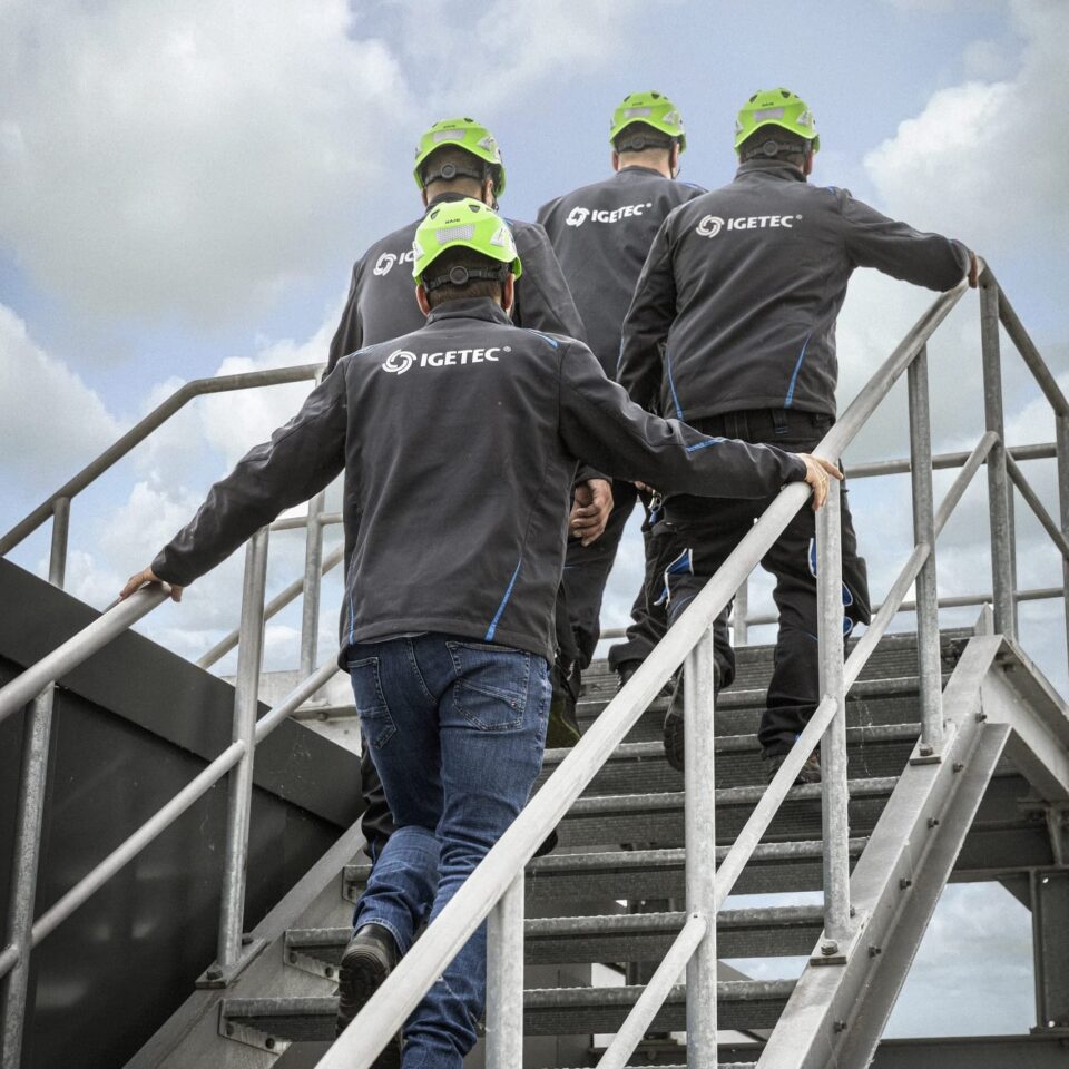 Arbeiter auf Treppe mit grünen Helmen.