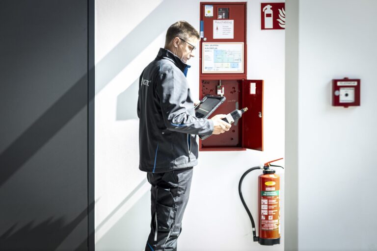 Mann inspiziert Feuerlöscher und Sicherheitsausrüstung.