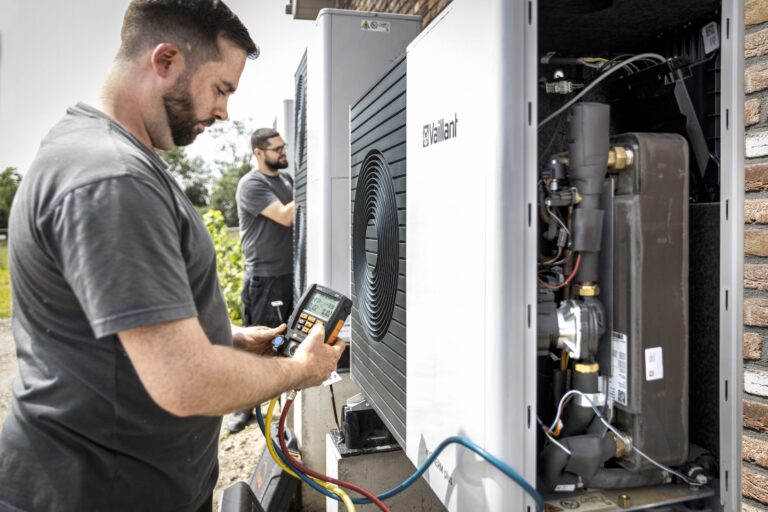 Techniker überprüft Wärmepumpe mit Messgerät im Freien.