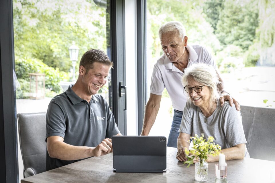 Menschen lachen zusammen vor einem Tablet.