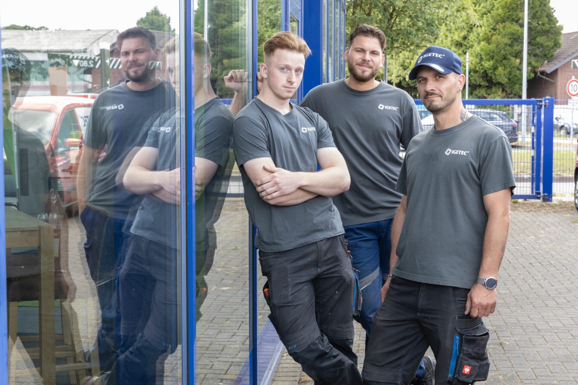 Drei Männer in Arbeitskleidung vor Gebäudefenster