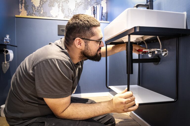 Installateur repariert Waschbecken in modernem Badezimmer