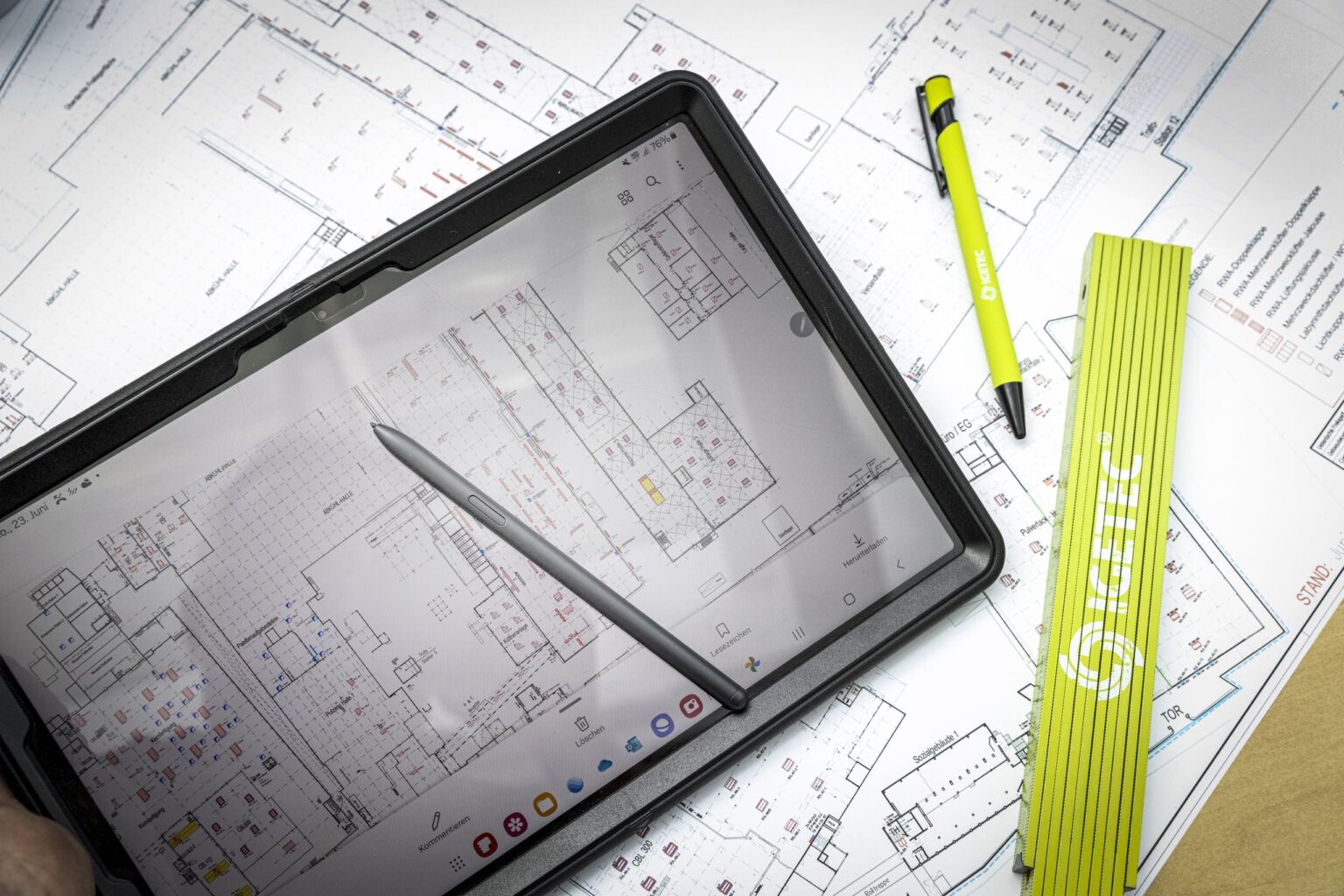 Tablet mit Bauplänen und Zeichenwerkzeugen auf Tisch