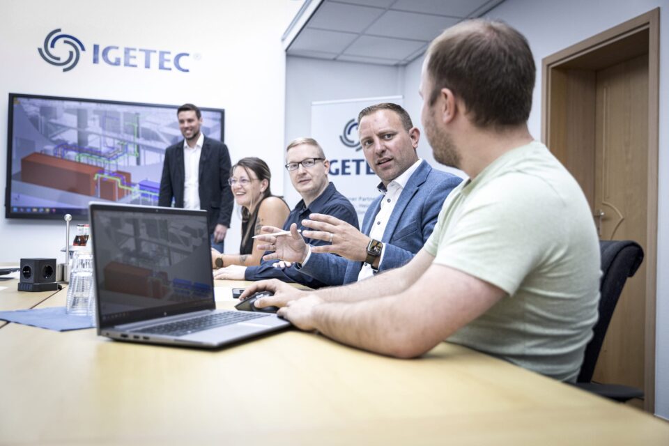 Team diskutiert Projektplan im Konferenzraum mit Monitor.